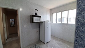 Eine kleine Küche mit Kühlschrank, Mikrowelle und Mixer auf einer Ablagefläche.