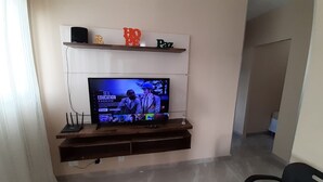 Ein Flachbildfernseher an der Wand, darunter ein Unterhaltungsschrank aus Holz.