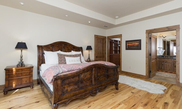 Une chambre à coucher avec un lit en bois, des tables de chevet, un tapis blanc et une armoire en bois.