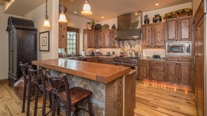 Una cocina amplia con una isla grande, armarios de madera y encimera de piedra.