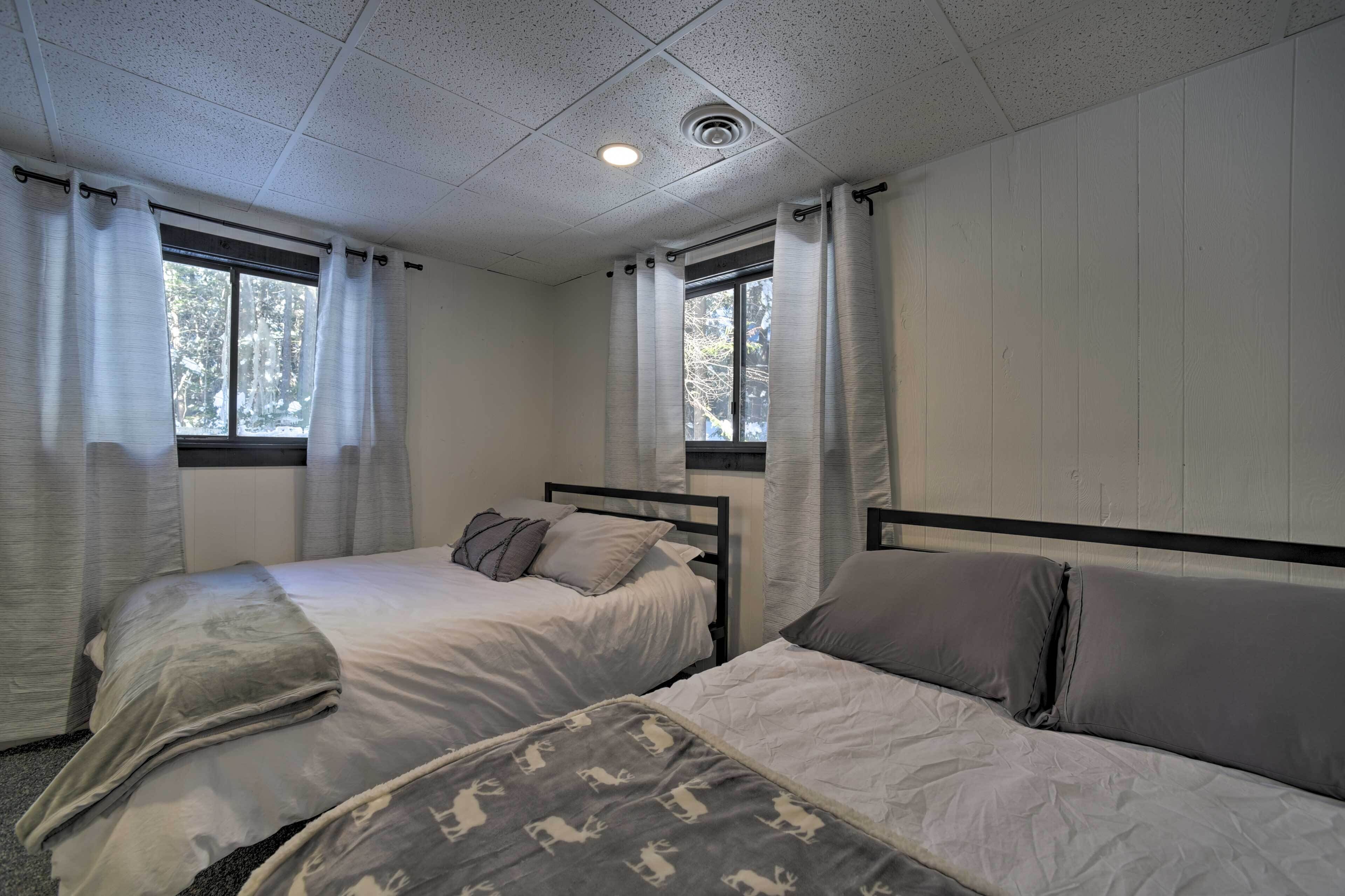 Une chambre avec deux lits, une fenêtre et un luminaire au plafond.