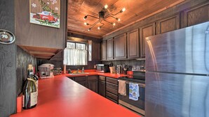 Una cocina moderna con armarios de madera, un refrigerador de acero inoxidable y una encimera roja.