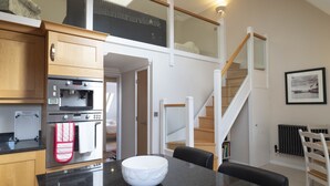 A modern kitchen with a black countertop, a white bowl, and wooden cabinets. - Adelaide Place (Canterbury)