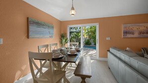 Uma área de refeições com uma mesa posta para quatro pessoas, um banco e um sofá.