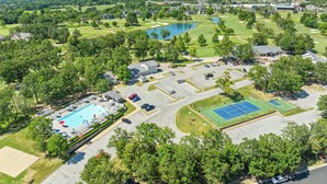 Vue aérienne d’un terrain de golf avec une piscine, des courts de tennis et un parking.