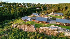 A cluster of modern cabins with metal roofs, surrounded by a forested landscape. - Cabin Oslofjord -sleeps14-seaview-familyfriendly (Frogn)
