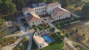 Une vue aérienne d’un vaste domaine comprenant plusieurs bâtiments, une piscine et de nombreux espaces verts.