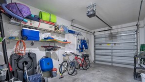 Eine Garage mit Fahrrädern, einem blauen Wagen und verschiedenen Werkzeugen auf Regalen.