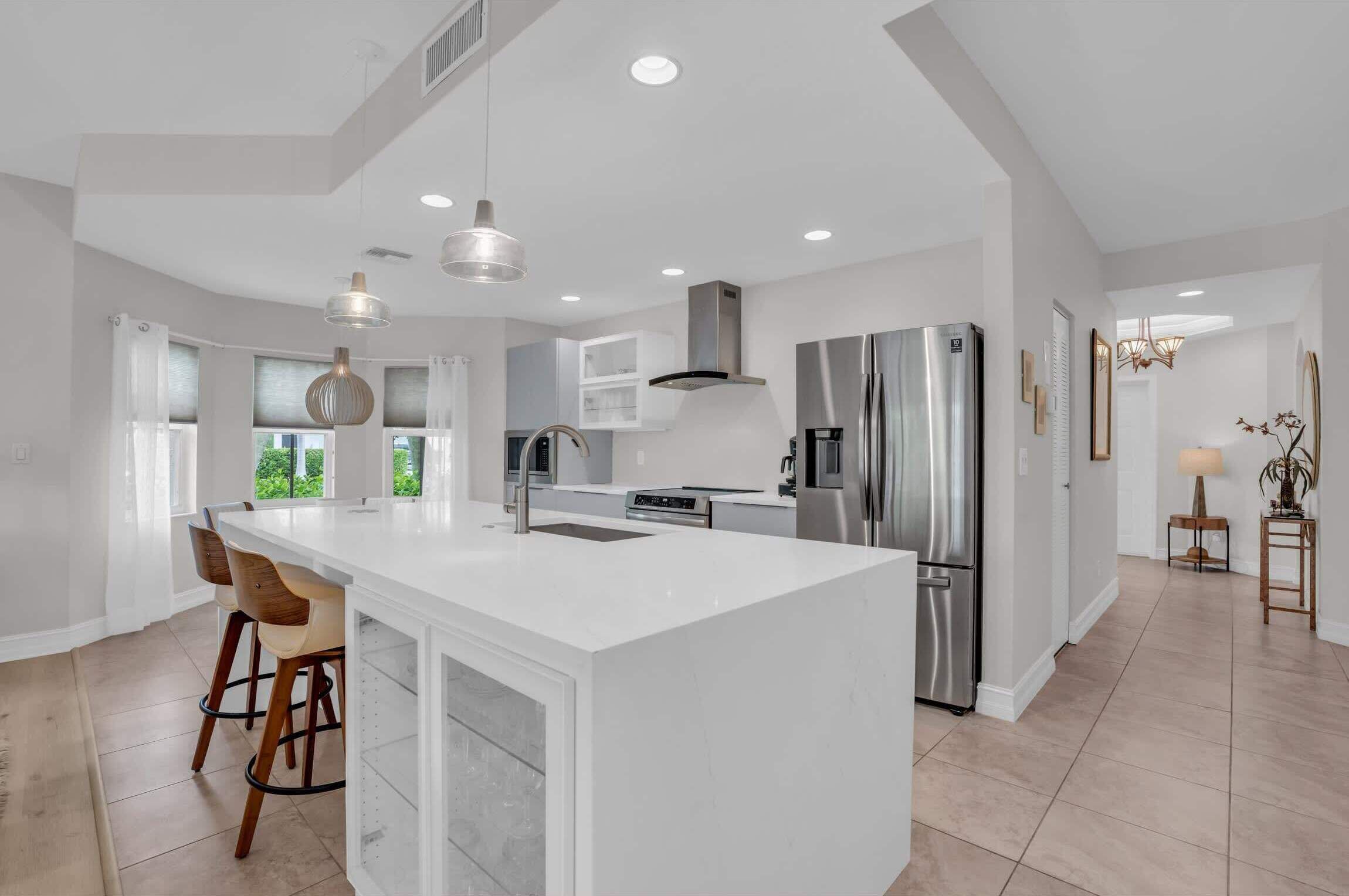 A modern kitchen with a large island, stainless steel appliances, and pendant lighting.