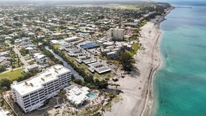 Eine Luftaufnahme einer Küstenstadt mit Strand, Gebäuden und einem Steg.