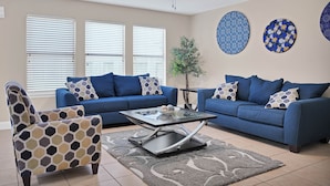 A living room with two sofas, a coffee table, and a patterned armchair.