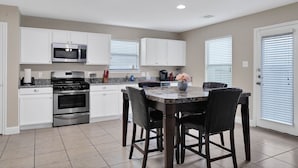 A modern kitchen with white cabinets, stainless steel appliances, and a marble countertop.
