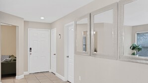 A hallway with beige walls, white doors, and a large mirror.
