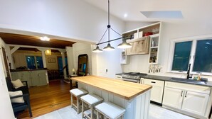 Une cuisine moderne avec un îlot central en bois, des tabourets de bar et un four encastré.