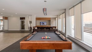 Relax in this spacious indoor recreational area with a pool table, comfortable sofa, and flat-screen TV.