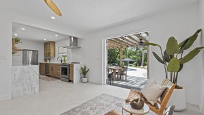 Una cocina moderna con una isla de mármol, armarios de madera y un comedor con mesa y sillas.