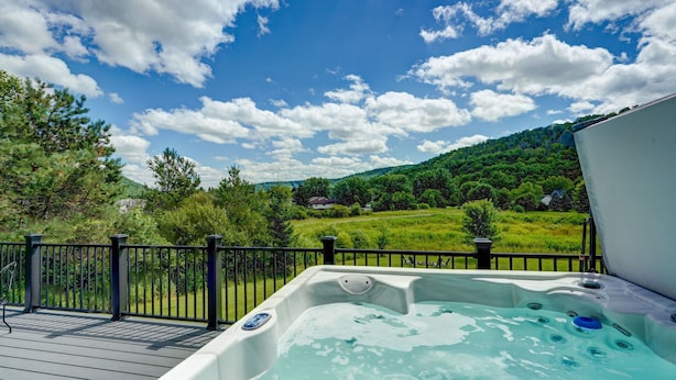 Un jacuzzi en una terraza con vistas a un paisaje verde y colinas.