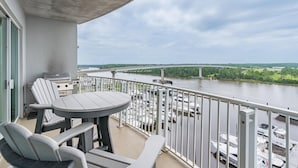 Een balkon met uitzicht op een rivier en een brug, een tafel en stoelen.