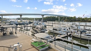 Een jachthaven met aangemeerde boten, een overdekt zitgedeelte en een brug op de achtergrond.