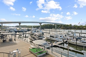 A marina with boats docked, a covered seating area, and a bridge in the background.