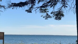 Une vue d’un lac, avec une zone herbeuse au premier plan et un panneau indicateur en bois.