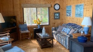 Un salon chaleureux avec des murs en bois, un canapé, une table basse et un téléviseur.