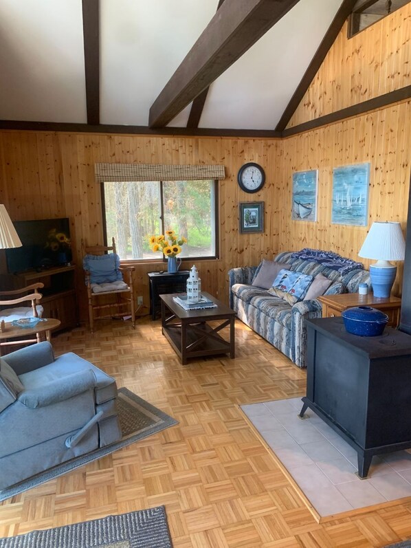 A cozy living room with wooden walls, a sofa, a coffee table, and a TV.