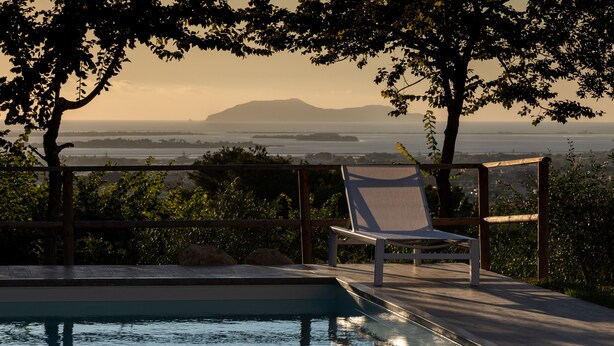 Un espace piscine avec vue sur l’océan et une chaise longue.