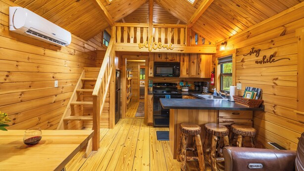 L’intérieur d’un chalet en bois comprend une cuisine, un coin bar et un escalier.