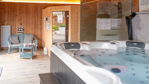Ett spa-rum med träinredning, en massagebänk och ett stort bubbelbad.