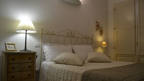A bedroom with a bed, bedside lamps, a dresser, and a wardrobe.