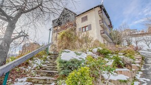 A multi-story building with balconies, a staircase leading up to it, and snow on the ground. - Les Fauvettes - appartement vue imprenable sur montagne (Embrun)