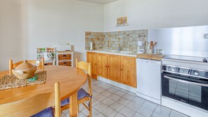 A compact kitchen with wooden cabinets, a white countertop, and a built-in dishwasher. - Les Fauvettes - appartement vue imprenable sur montagne (Embrun)