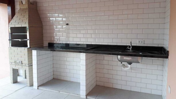 Eine Küche mit weiß gefliestem Fliesenspiegel, einer schwarzen Arbeitsplatte und einem Backofen aus Ziegelsteinen.