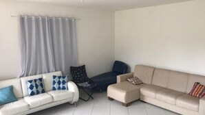 Ein Wohnzimmer mit einem weißen Sofa, einem blauen Sessel und einem beigen Sofa.