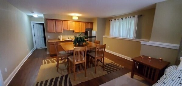 A compact kitchen with wooden cabinets, a dining table with chairs, and a small refrigerator. - Beautiful and Cozy Lake Geneva Home for Rent (Lake Geneva)