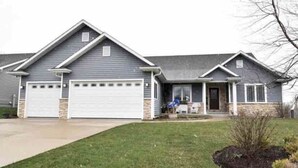 A two-story house with a garage, a front porch, and a well-maintained lawn.