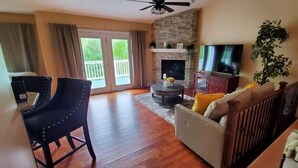 A spacious living room with a fireplace, a television, and a balcony with curtains.