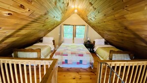 Een gezellig zolderkamer met twee bedden, een houten plafond en een raam.
