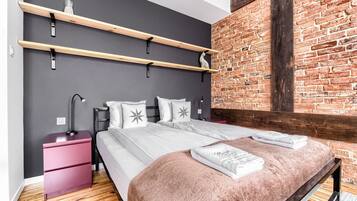 Un dormitorio moderno con cama, dos mesitas de noche, una pared de ladrillo y estantes de madera.
