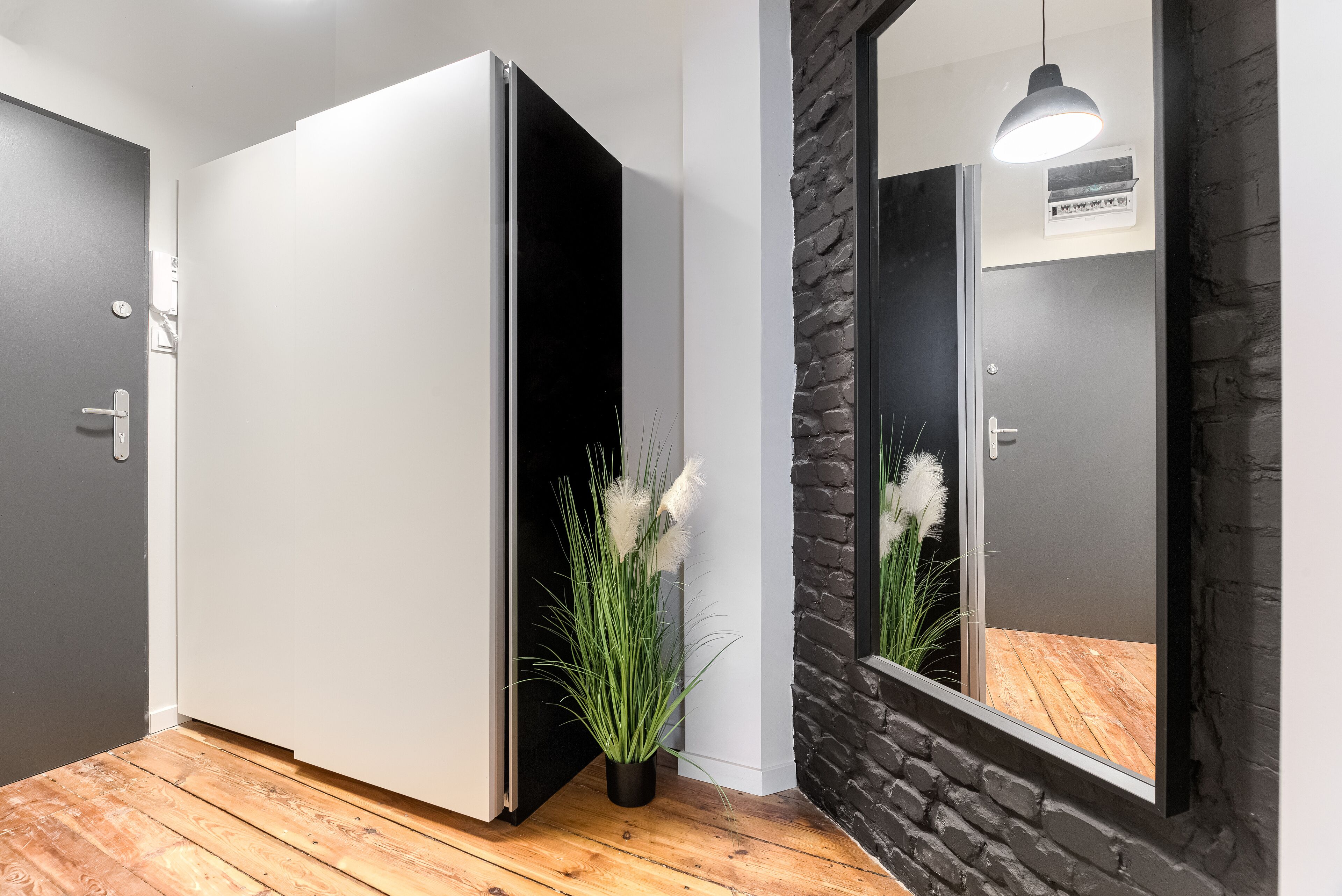 Une chambre moderne dotée d’une porte coulissante, d’une plante en pot, d’un miroir et d’un luminaire suspendu.