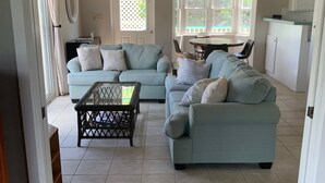 A spacious living area with two light blue sofas, a coffee table, and a dining table with chairs. - Breezy Hilltop, Hart Bay View, only minutes from town (Cruz Bay)