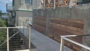 A covered outdoor area with a concrete wall, wooden benches, and a metal railing. - Breezy Hilltop, Hart Bay View, only minutes from town (Cruz Bay)