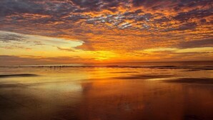 A beach scene with a sunset, calm water, and a distant pier. - 3 Bdrm Waterfront Villa in Harbour Town- Relax to the sounds of the Calibogue (Hilton Head Island)