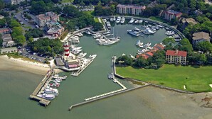 An aerial view of a marina with boats docked, a lighthouse, and surrounding buildings. - 3 Bdrm Waterfront Villa in Harbour Town- Relax to the sounds of the Calibogue (Hilton Head Island)