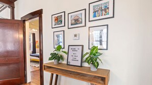 A hallway with a wooden door, a welcome sign, and several framed pictures on the wall.