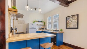 A modern kitchen with a wooden island, bar stools, and a chalkboard menu.