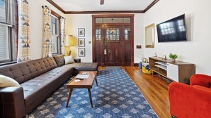 A living room with a brown sofa, a red armchair, a wooden coffee table, and a blue patterned rug.