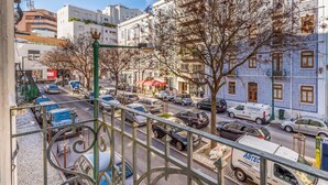 A city street with parked cars, a white van, and buildings with blue and white facades. - GuestReady - Castle - Apt for 4 guests in Saldanha (Lisboa)