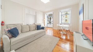 A modern living room with a sofa, a dining table, and a TV. - GuestReady - Castle - Apt for 4 guests in Saldanha (Lisboa)